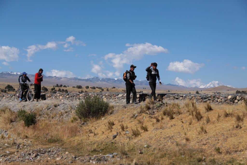 Les étudiants en Bolivie marchent sur un terrain accidenté lors de leur trajet vers l'école. Ils sont dans les plaines et les montagnes sont au loin.