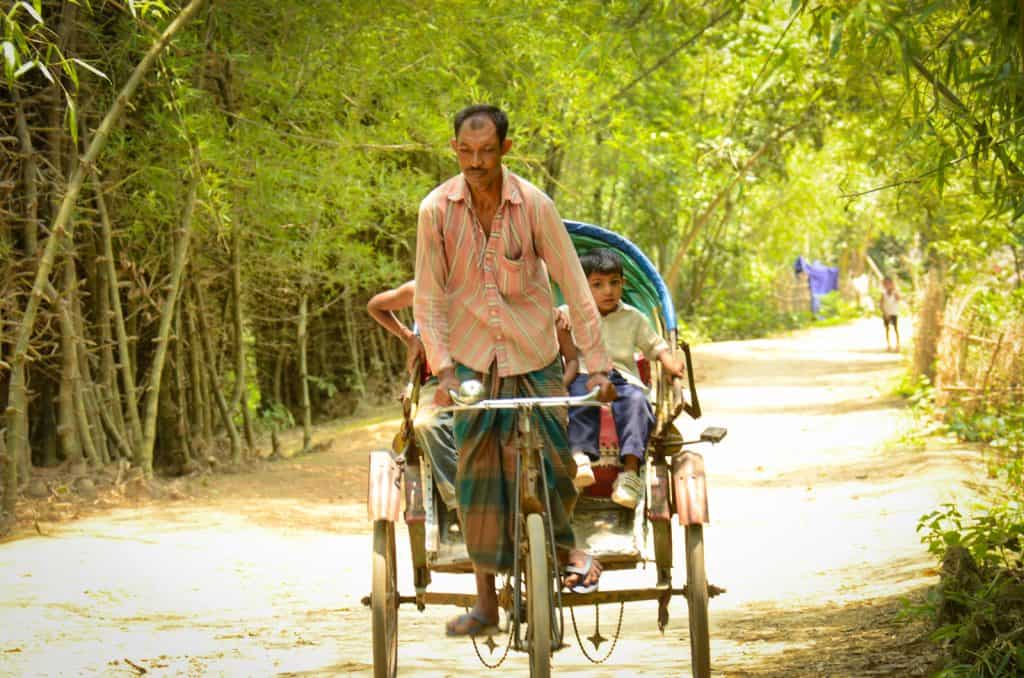 Un homme conduit un pousse-pousse avec des enfants à cheval dessus