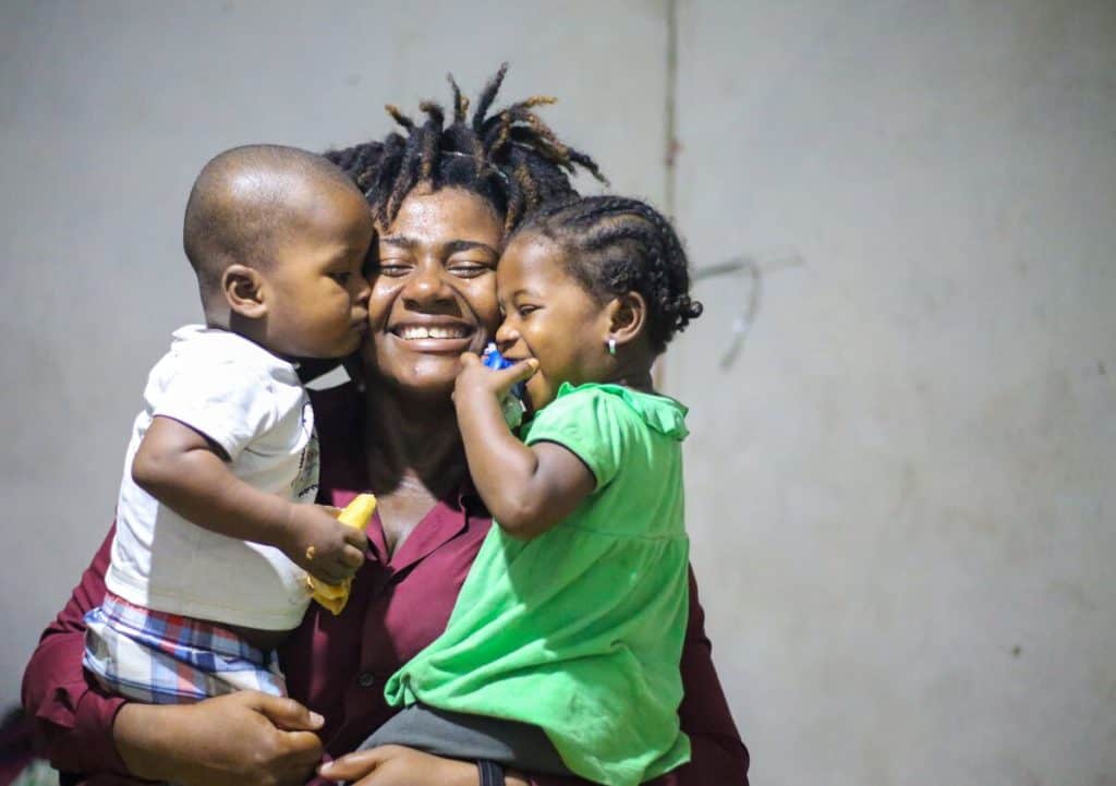 Fabiola est une mère forte en Haïti qui est vue souriant et tenant ses tout-petits jumeaux.