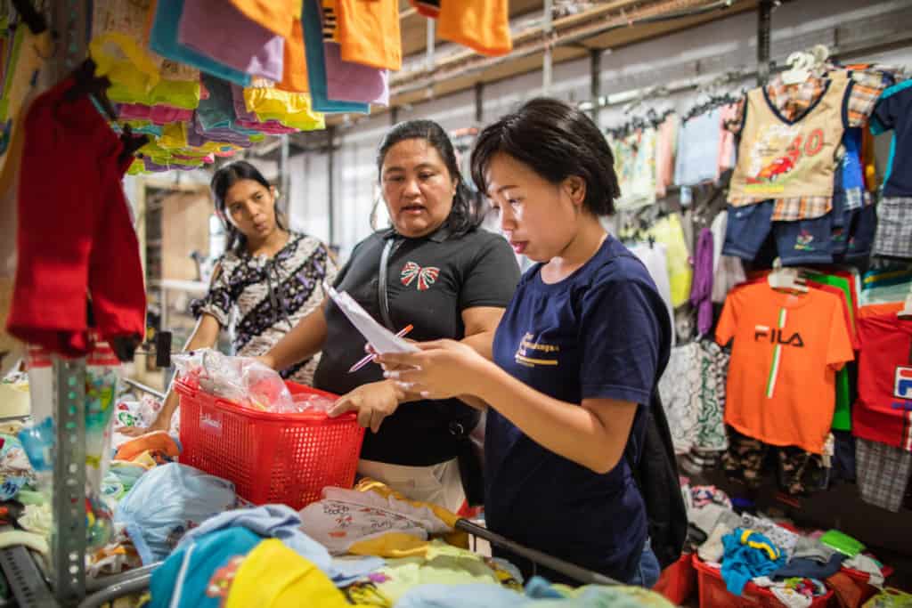 Achats de Noël en Indonésie Injilia Mundung (à droite) vérifie une liste de courses pour s'assurer que 15 bénéficiaires de Survival reçoivent des cadeaux de Noël appropriés. Injilia et Donna Mangindaan (au milieu) font leurs courses dans l'un des magasins de vêtements de la ville de Manado.