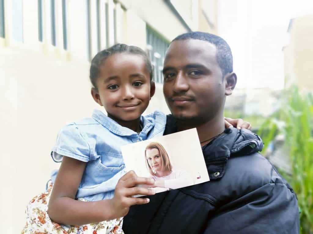 Sintayehu tient sa fille Lisa, qui tient une photo de l'ancien parrain de son père