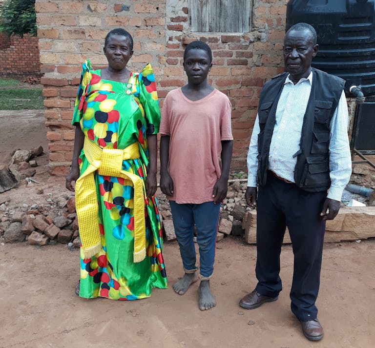 Sajja debout devant sa maison avec sa femme et son petit-fils. 