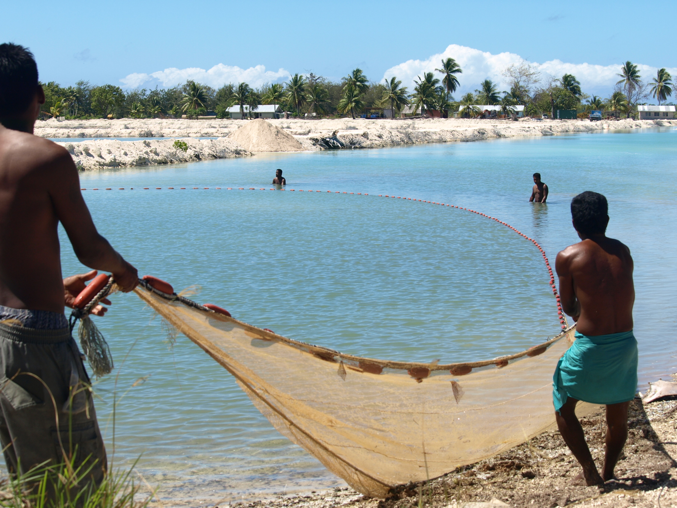 Un pêcheur jette son filet dans les eaux de Kiribati, illustrant les efforts locaux de réduction de la pauvreté. réduction de la pauvreté à Kiribati
