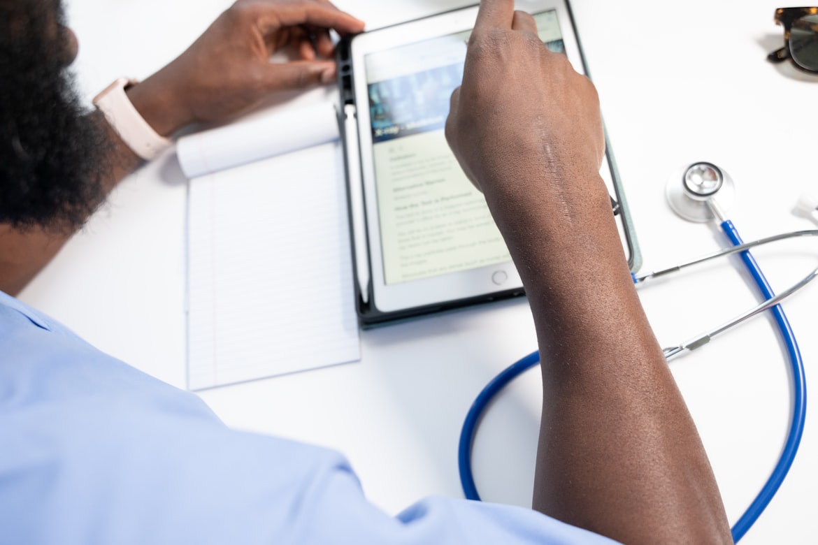 Homme utilisant une tablette dans une pièce lumineuse, initiative Innovate Health Africa. DHLSAT